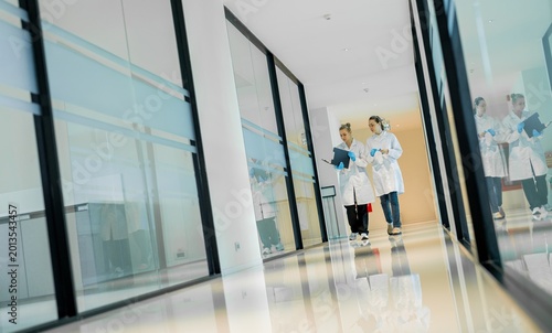 Two medical staff members walking in a hospital corridor while discussing patient care and daily tasks