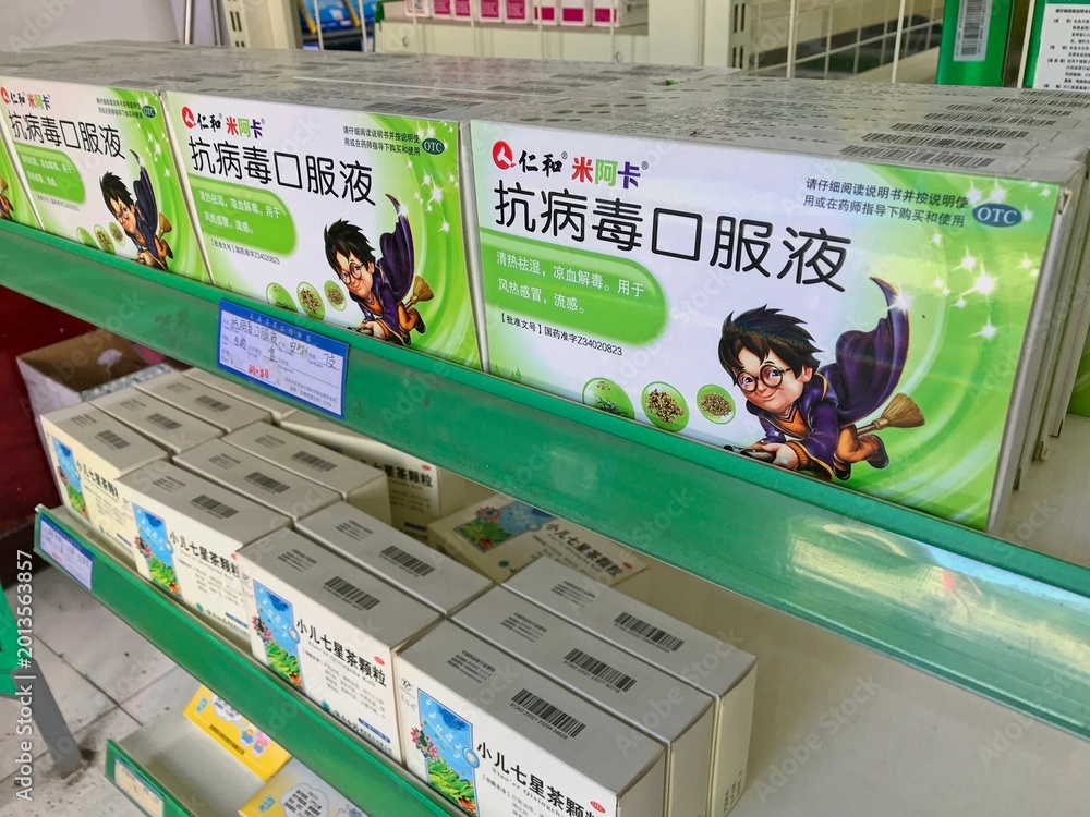 Fototapeta premium LIJIANG, CHINA - OCTOBER 26, 2017:Boxes of antiviral oral liquid by Jen and Miaka Pharmaceuticals, a Chinese medicine for throat relief displayed on green shelves in a local pharmacy in Lijiang Yunnan