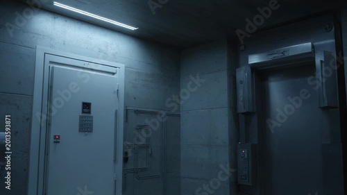 Concrete walls and a robust security door with keypads lead to a restricted area, alongside an elevator in a dimly lit, high security industrial facility