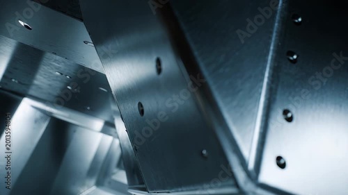 Brushed metal panels forming an industrial abstract structure with sharp geometric angles, creating a repetitive pattern and conveying strength, technology, and engineering