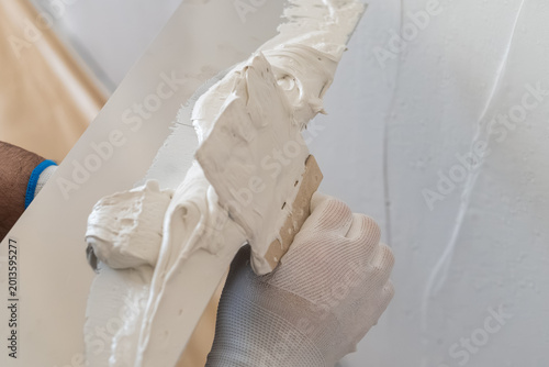 Foto Skilled professional applying a smooth layer of plaster using a trowel on interior wall surface
