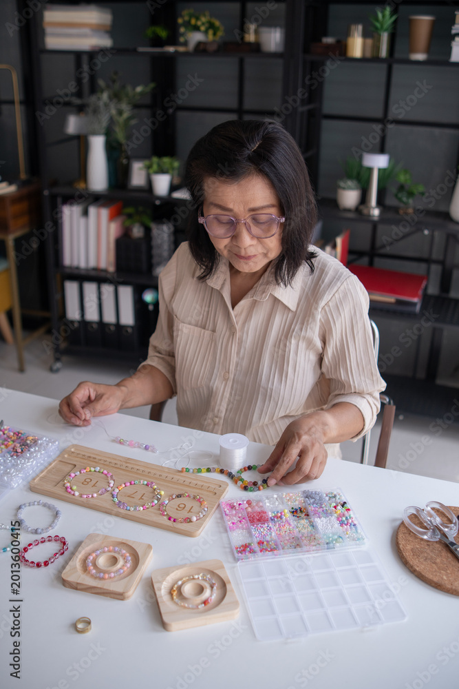 Fototapeta premium Mature asian woman&nbsp;making handmade jewellery accessories handcraft hobby