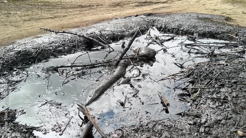 Pits with crude oil and salt water near the mud volcano in Starunya, Ukraine. Unique geological phenomenon with oil seeps and mineral deposits on the ground. Environmental and energy background.