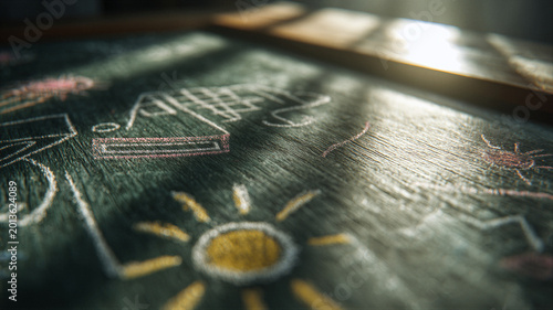 Cinematic macro of a green chalkboard featuring soft chalk drawings of a house, sun, and petals. Warm morning light highlights floating dust and texture, leaving copy space for education banners.