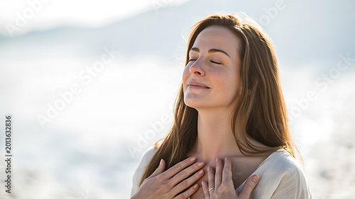 Peaceful young woman with eyes closed touching chest in soft natural light outdoor portrait