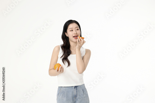 Canvas Print Young woman pretending to eat fresh orange on white background