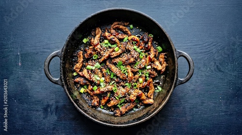Savory Beef Stir Fry With Green Onions and Sesame Seeds in Cast Iron Wok on Dark Table Asian Dining Presentation