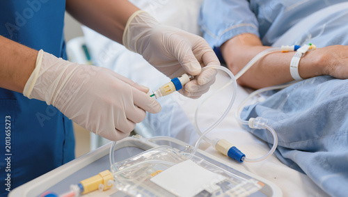 Medical professional connecting IV drip to patient's hand in hospital setting