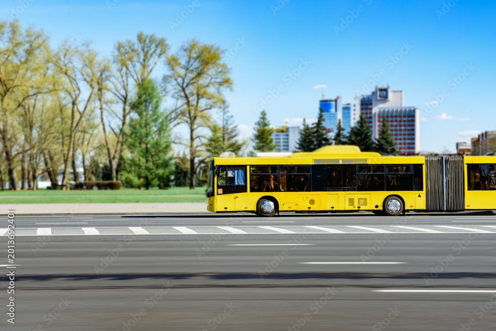 Obraz premium A yellow city bus driving along Minsk avenue road. Public transport in Belarus.