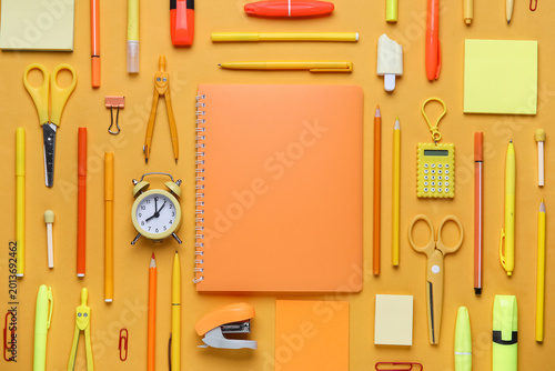 Фотография Different school stationery supplies and alarm clock on orange background