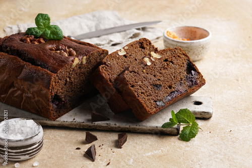 Close-up of vegetarian chocolate banana brownie slices made with red lentils on a ceramic board. Healthy gluten-free dessert on beige background