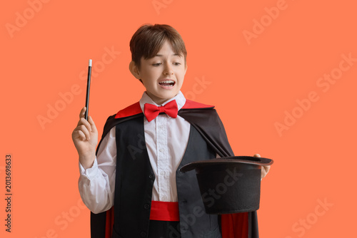 Photos Little magician with wand and hat on orange background