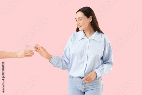 Young woman taking glass of...