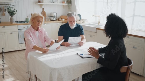 Female insurance agent consulting senior people about insurance property program . Elderly spouses thinking about buying new house or automobile with bank credit, meeting with professional lawyer