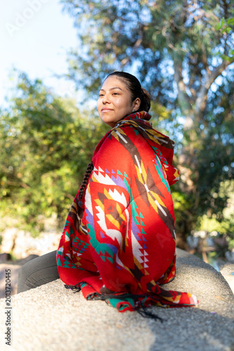 Foto Indigenous Peruvian woman sitting in park wearing colorful traditional poncho