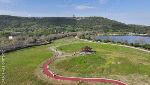 Aerial View of Green Park with Winding Path and Lakeside Pavilion