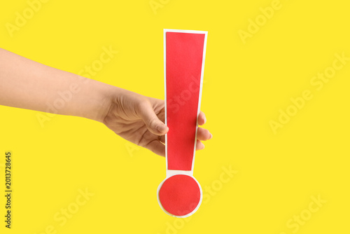 Foto Female hand with red paper exclamation mark on yellow background, closeup
