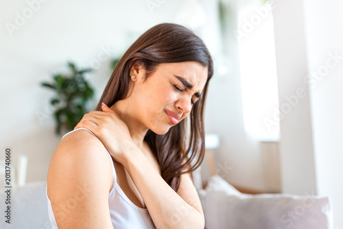 Shoulder pain. Upper arm pain, People with body-muscles problem, Healthcare And Medicine concept. Attractive woman sitting on the bed and holding painful shoulder with another hand. Muscle strain.