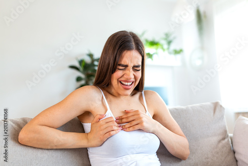 Chest pain. Young woman with body problem, Healthcare and Medicine concept. Attractive woman suffering from heartache, holding painful chest with hands and crying. Squeezing heart disease symptom.
