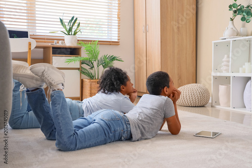Cute African-American children watching cartoons on TV at home