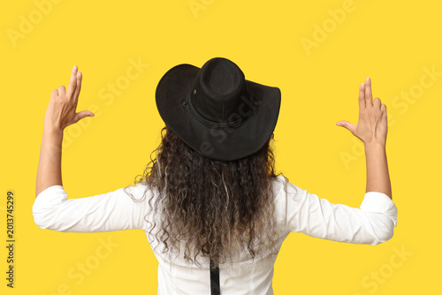 Obraz na płótnie Beautiful African-American cowgirl making guns with her hands on yellow backgrou