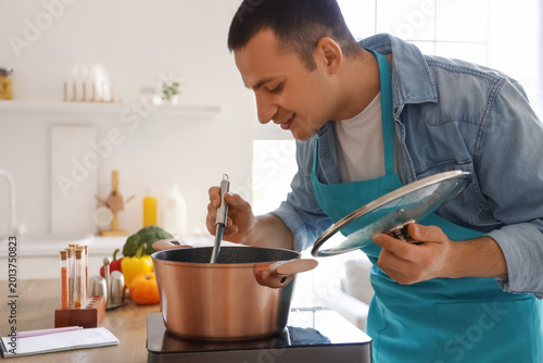 Young man cooking soup in a...