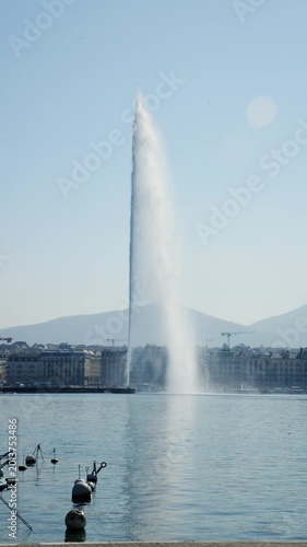Vertical video of the famous Jet d'Eau water fountain shooting high into the blue sky on Lake Geneva. Perfect B-roll for Swiss travel promotions and luxury tourism content.