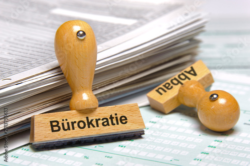 Canvastavla Ein Holzstempel ist beschriftet mit dem Aufdruck Bürokratieabbau und lehnt an ei
