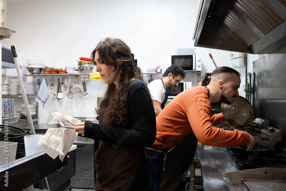 Naklejka premium Kitchen team actively working together preparing food in a professional restaurant setting