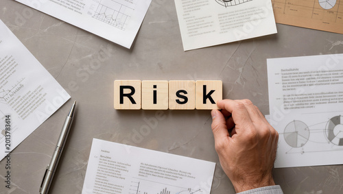 Mitigating Business Risk: Hand Arranging Wooden Tiles on Desk with Documents
