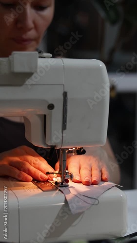 A close-up captures hands sewing blue fabric with a machine, carefully aligning the material. The clean, smooth stitches highlight the focus and expertise involved in the sewing process.