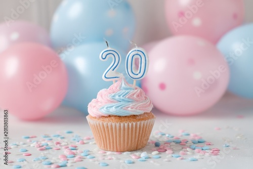 Festive birthday cupcake with pink and blue frosting and 