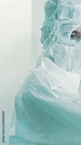 A scientist in a cleanroom, clad in protective gear, meticulously examines a blood sample in a medical laboratory, ensuring precision in pharmaceutical research.