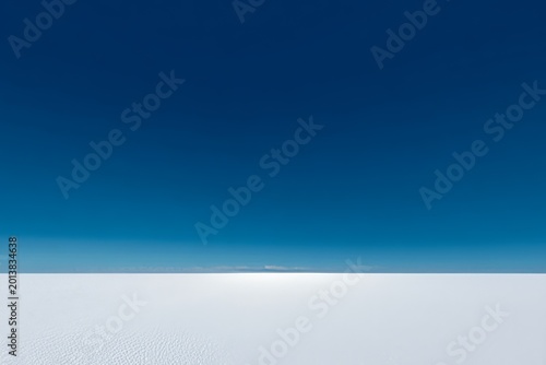 Vast blue sky and white desert horizon with textured surface