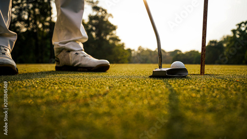 Golf clubs and balls on a green lawn in a beautiful golf course with morning sunshine.