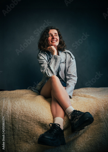 Beautiful young girl with beautiful legs smiling, exuding youthfulness and playfulness in a cozy, softly lit indoor setting, embracing joy in solitude and personal reflection