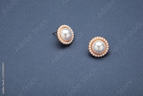 Stylish pearl earrings on blue background. Top view