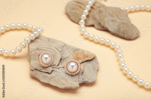 Beautiful pearl earring and necklace on stone on beige background