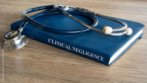 Clinical Negligence concept featuring a medical law textbook with a professional stethoscope on a rustic wooden office desk.