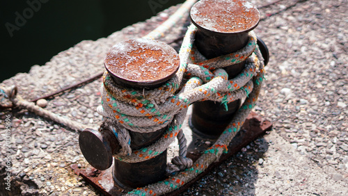rusty metal bollards with a thick mooring rope on a pier.