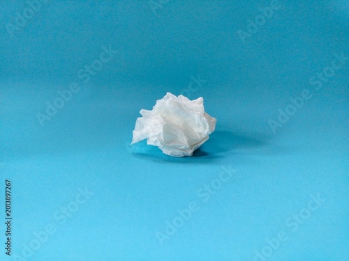 crumpled used paper tissue on blue