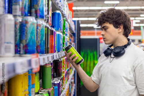 Foto Teenager reading canned drink label in supermarket, sugar caffeine and alcohol c