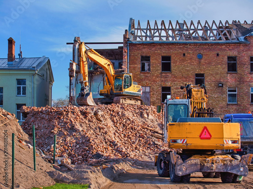 Bild auf Leinwand Yellow excavators working on demolition of old brick house
