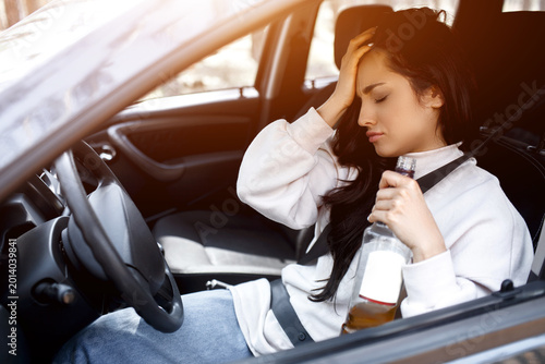 Drinking at the wheel. A drunk woman drives a car. Life threatening to drink alcohol and drive a car.