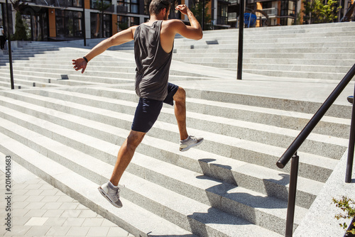 Young man exercising outside. Picture of jumping up process over several steps. Powerful energetic exercise or running. Jumping alone at urban buildings.