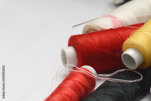 Sewing thread and needles flat lay on white background with copy space