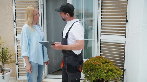 Delivery man having a woman sign a clipboard for a package delivery service at her front door, confirming receipt and ensuring customer satisfaction with the courier