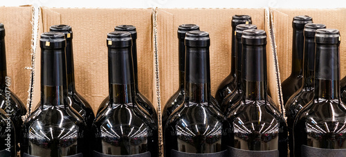 Rhythmic rows of dark glass wine bottles in cardboard shipping boxes