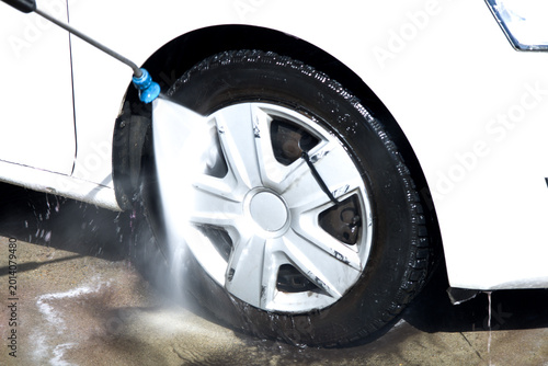 Konstfotografi Close-Up of Car Wheel Being Cleaned with High-Pressure Water Jet at Car Wash