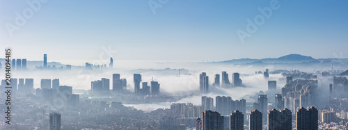 Fotografia Skyscrapers in the City Emerging from Morning Fog